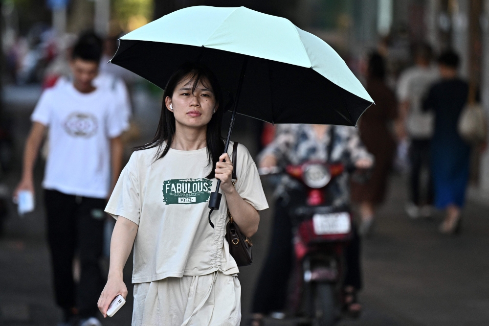A woman walks during a hot day in Wuhan, central China's Hubei province on August 1, 2024. (Photo by Pedro Pardo / AFP)
 