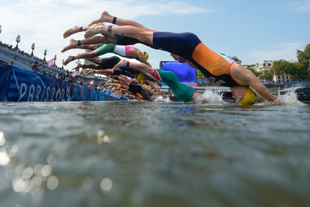 Athletes dive into the Seine river as they start the swimming stage of the men's individual triathlon at the Paris 2024 Olympic Games in central Paris on July 31, 2024. (Photo by David Goldman / POOL / AFP)
