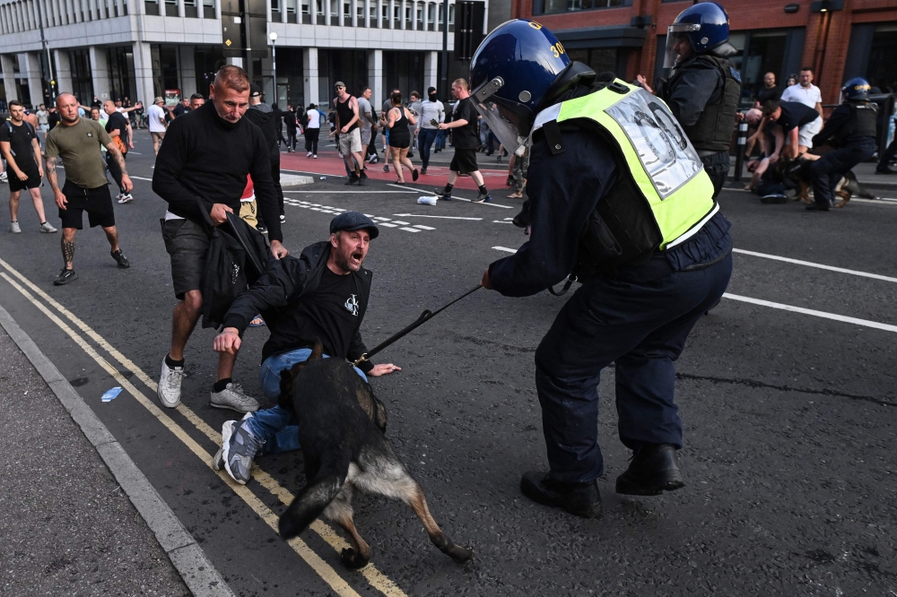 A police dog bites a protester in Bristol, southern England, on August 3, 2024 during the 'Enough is Enough' demonstration held in reaction to the fatal stabbings in Southport on July 29. Photo by JUSTIN TALLIS / AFP