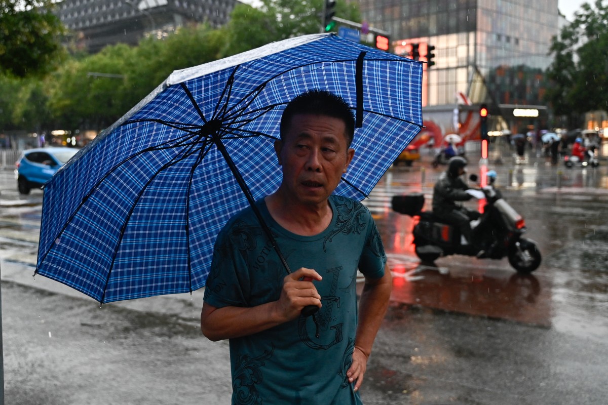 A man holding an umbrella walks during a rainstorm in Beijing on July 30, 2024. Photo by Pedro PARDO / AFP.