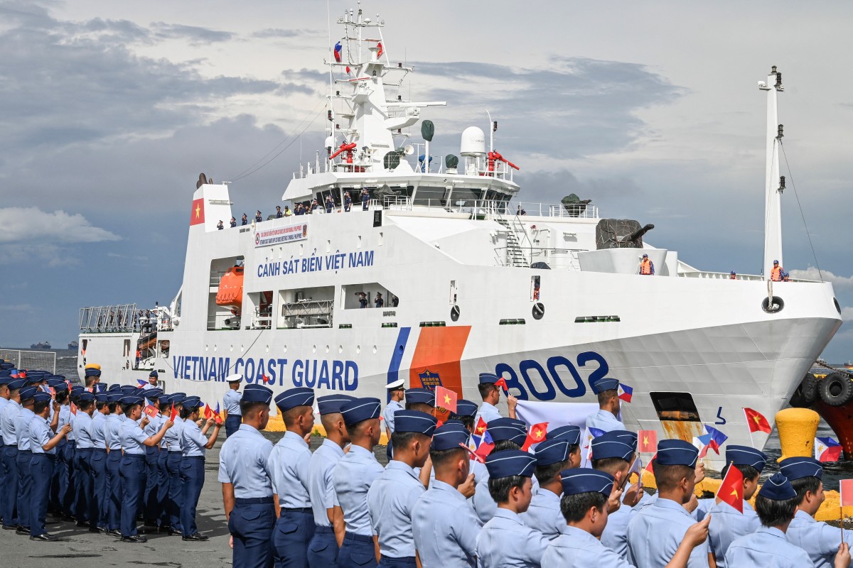 Philippine Coast Guard personnel wave flags as a Vietnam Coast Guard ship makes a port call during a goodwill visit at a port in Manila on August 5, 2024. Photo by JAM STA ROSA / AFP.