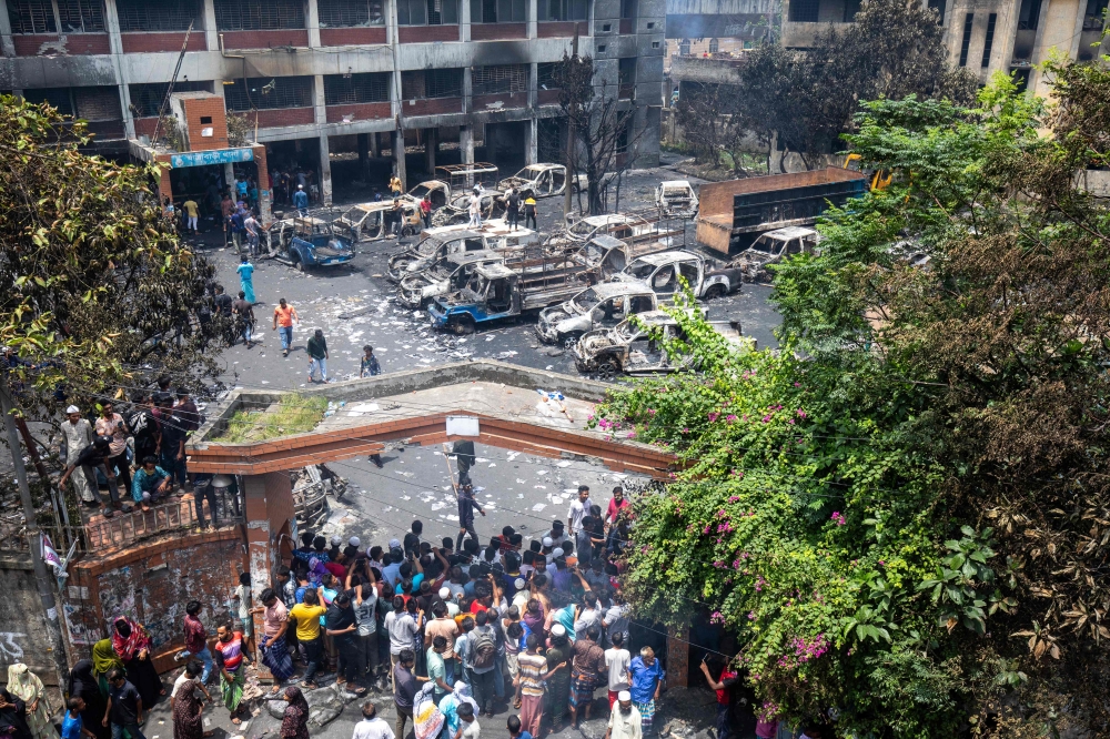 People gather to see burnt Jatrabari police station as anti-government protestors set fire in Dhaka on August 6, 2024, after former prime minister Sheikh Hasina fled the country. (Photo by Abdul Goni / AFP)
