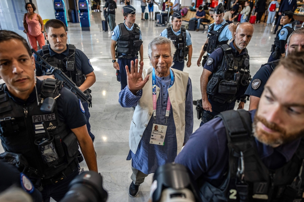 Bangladesh's finance pioneer Muhammad Yunus (centre) is escorted by French police personnel as he arrives at Roissy-Charles de Gaulle Airport, north of Paris on August 7, 2024, enroute to Bangladesh. (Photo by Luis Tato / AFP)
