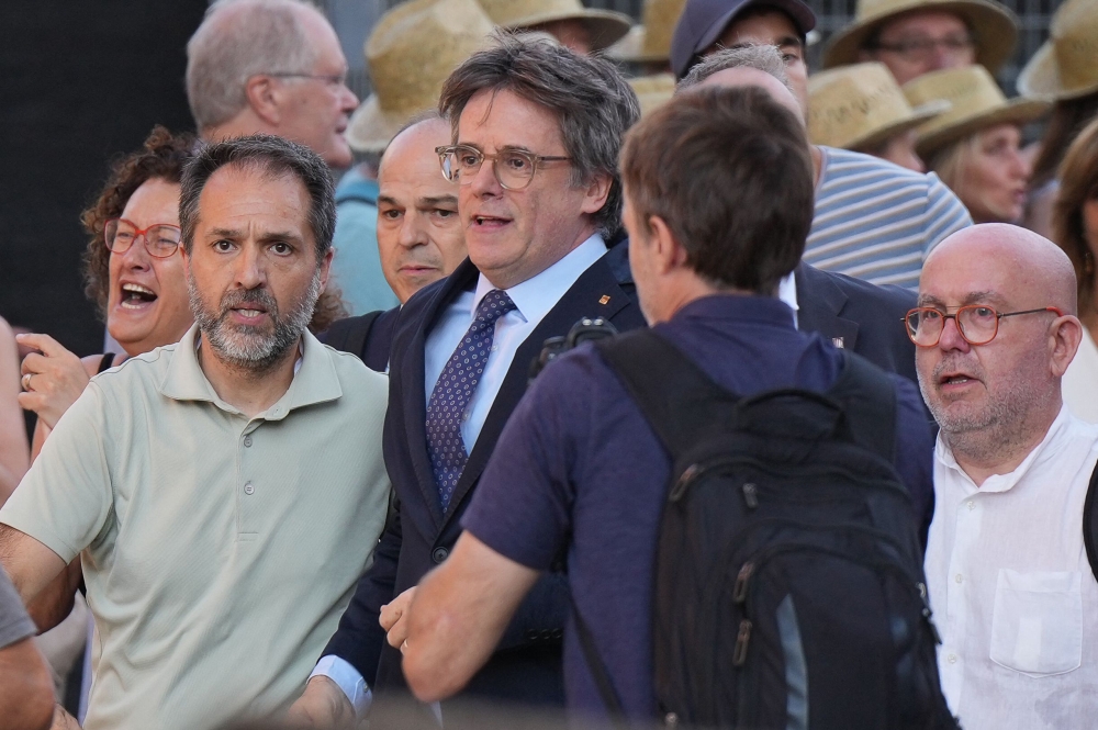 Catalonia's exiled separatist leader Carles Puigdemont (C) arrives with his lawyer Gonzalo Boye (R) and Junts per Catalunya's General Secretary Jordi Turull (3rd-L) as his hardline separatist JxCAT party has scheduled a welcome ceremony, ahead of an investiture vote at the Parliament of Catalonia, in Barcelona on August 8, 2024. (Photo by Cesar Manso / AFP)
