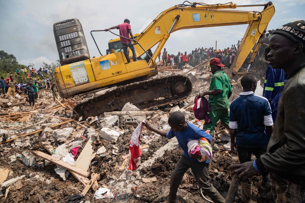 People look on as an excavator helps search for people trapped under debris after a landfill collapsed in Kampala on August 10, 2024. Photo by BADRU KATUMBA / AFP