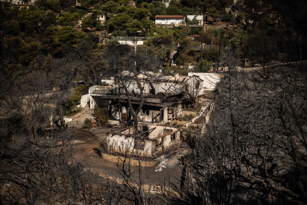 This photograph shows a view of a burnt houses following a wildfire that hit the north-eastern suburbs of athens, near Penteli, suburb of athens, on August 13, 2024. On August 13, 2024, Greece continued for the third consecutive day to fight a fire in the north-eastern suburbs of athens, which has killed one person, forced thousands from their homes and polluted the air in the capital. (Photo by Angelos TZORTZINIS / AFP)
