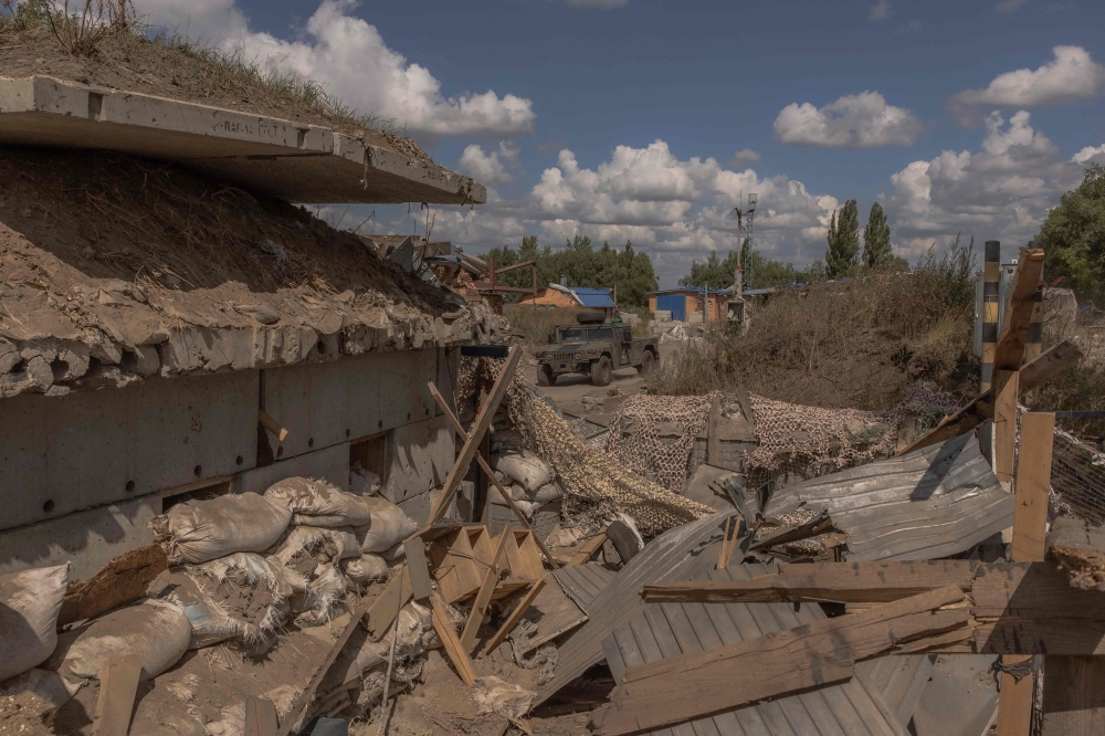 Ukrainian servicemen drive a Humvee military vehicle past a destroyed border crossing point with Russia, in the Sumy region, on August 14, 2024. (Photo by Roman PILIPEY / AFP)
