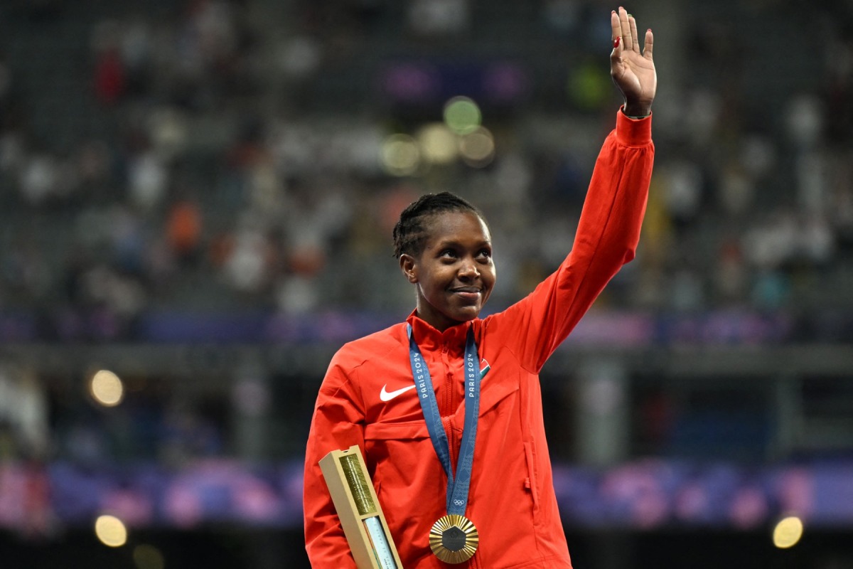 Gold medallist Kenya's Faith Kipyegon celebrates on the podium after competing in the women's 1500m final of the athletics event during the Paris 2024 Olympic Games at Stade de France in Saint-Denis, north of Paris, on August 10, 2024. (Photo by MARTIN BERNETTI / AFP)
