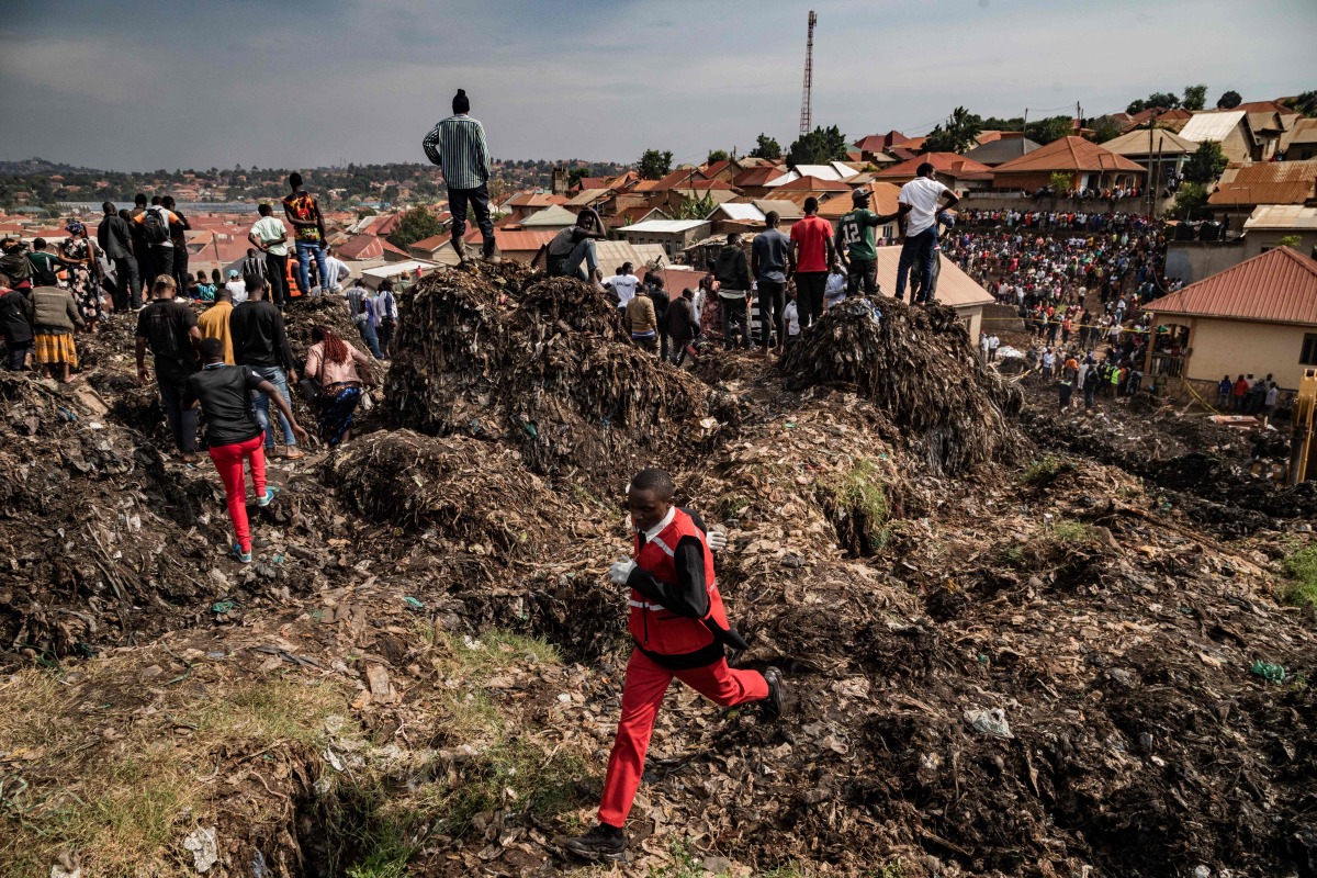 A Red Cross officer runs for help following a landfill collapse in Kampala on August 10, 2024. (Photo by BADRU KATUMBA / AFP)

