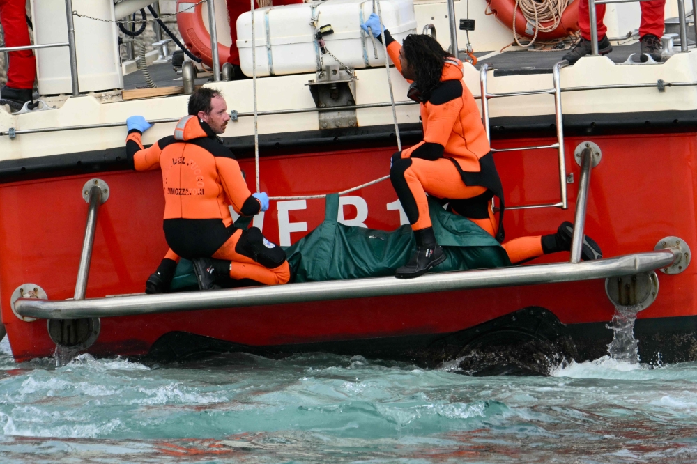 Divers of the Vigili del Fuoco, the Italian Corps. of Firefighters arrive with a body bag at the back of the boat in Porticello near Palermo, on August 21, 2024 two days after the British-flagged luxury yacht Bayesian sank. (Photo by Alberto PIZZOLI / AFP)

