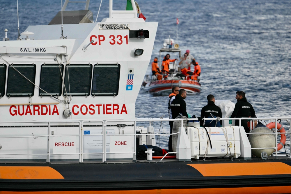Italian Coast Guards carry a body on a rescue boat in Porticello harbor near Palermo, with a third body at the back of the boat on August 21, 2024, two days after the British-flagged luxury yacht Bayesian sank. (Photo by Alberto PIZZOLI / AFP)
