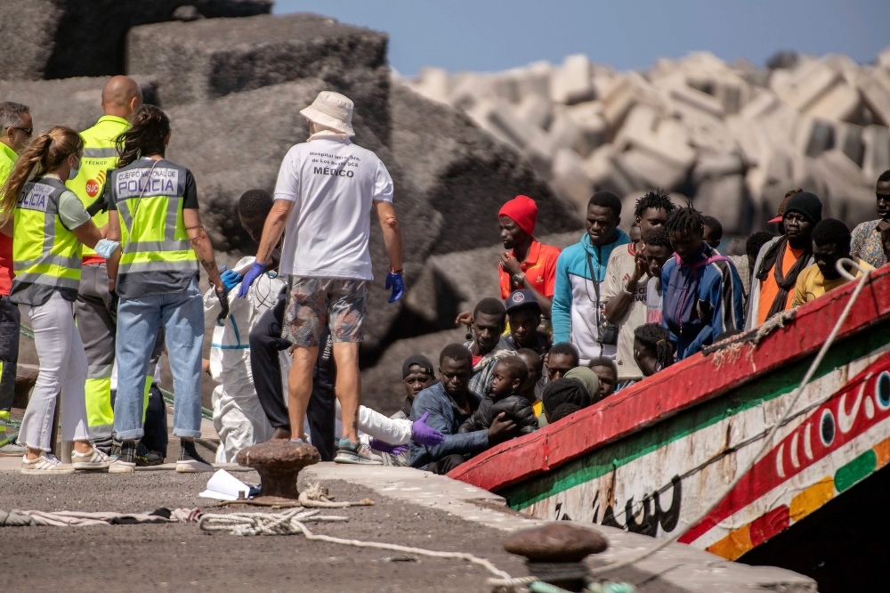 Members of police forces and emergency services help 175 migrant people on board a boat, upon its arrival at Restinga port on the Canary island of El Hierro on August 18, 2024. (Photo by Antonio Sempere / AFP)
