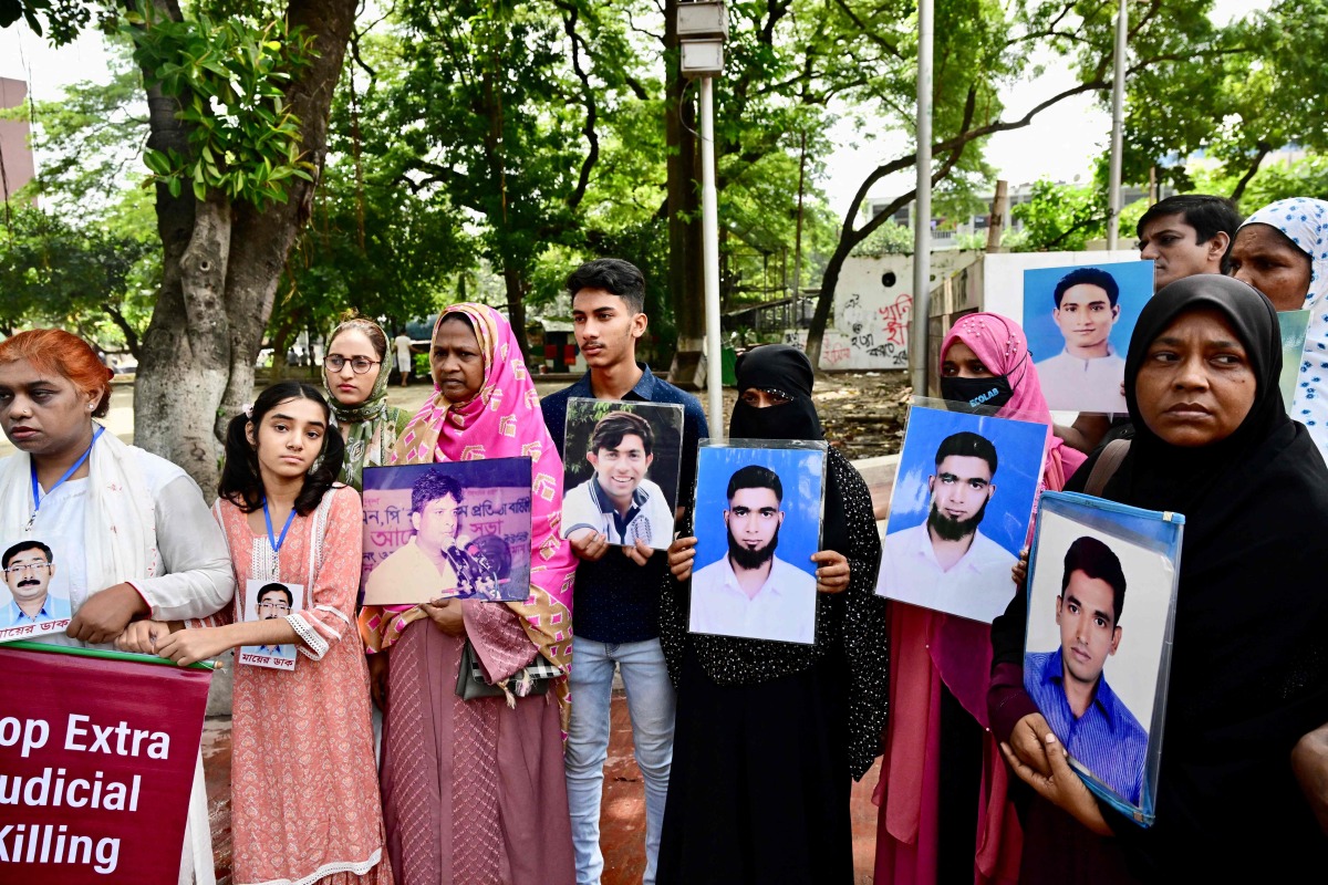 Relatives hold portraits of forcibly disappeared people, as they form a human chain to mark the International Day of the Victims of Enforced Disappearances, in Dhaka on August 30, 2024. (Photo by MUNIR UZ ZAMAN / AFP)
