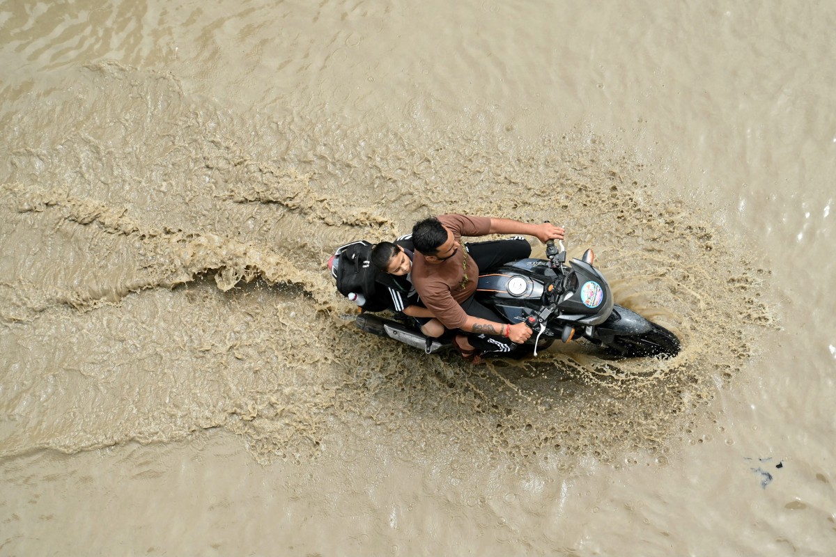 A motorcyclist rides through a flooded street after heavy monsoon rains in Amritsar on August 29, 2024. Photo by Narinder NANU / AFP.
