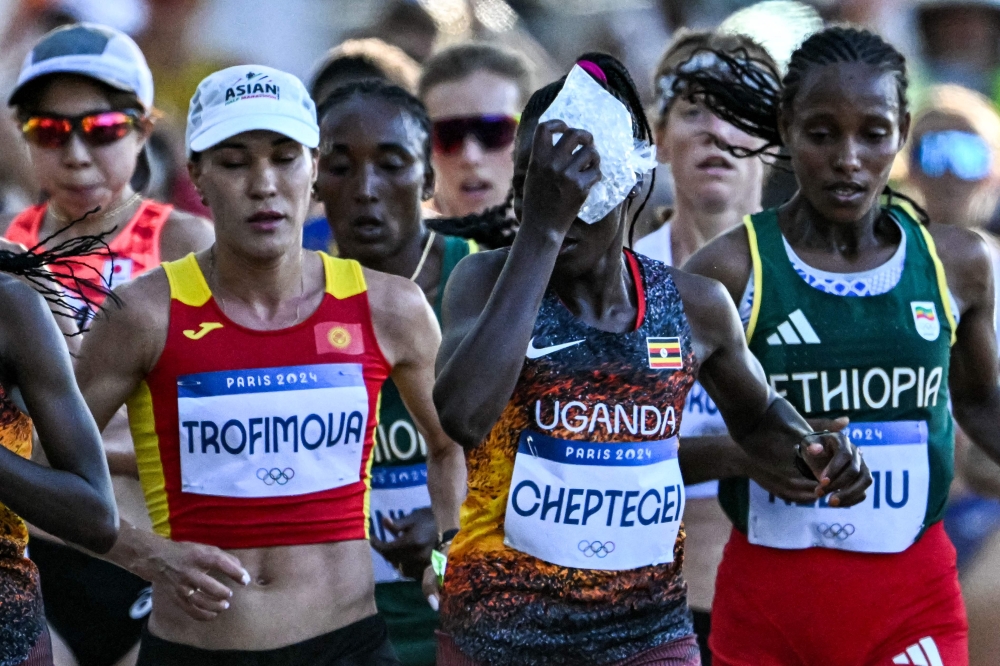(Files) Uganda's Rebecca Cheptegei (C) applies an ice bag on her head as she competes in the women's marathon at the Paris 2024 Olympic Games in Paris on August 11, 2024. (Photo by Kirill Kudryavtsev / AFP)
 