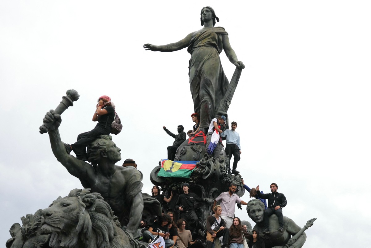 Protesters climbs on the statue 'Le Triomphe de la Republique' at Place de la Nation to demonstrate against the French President's 
