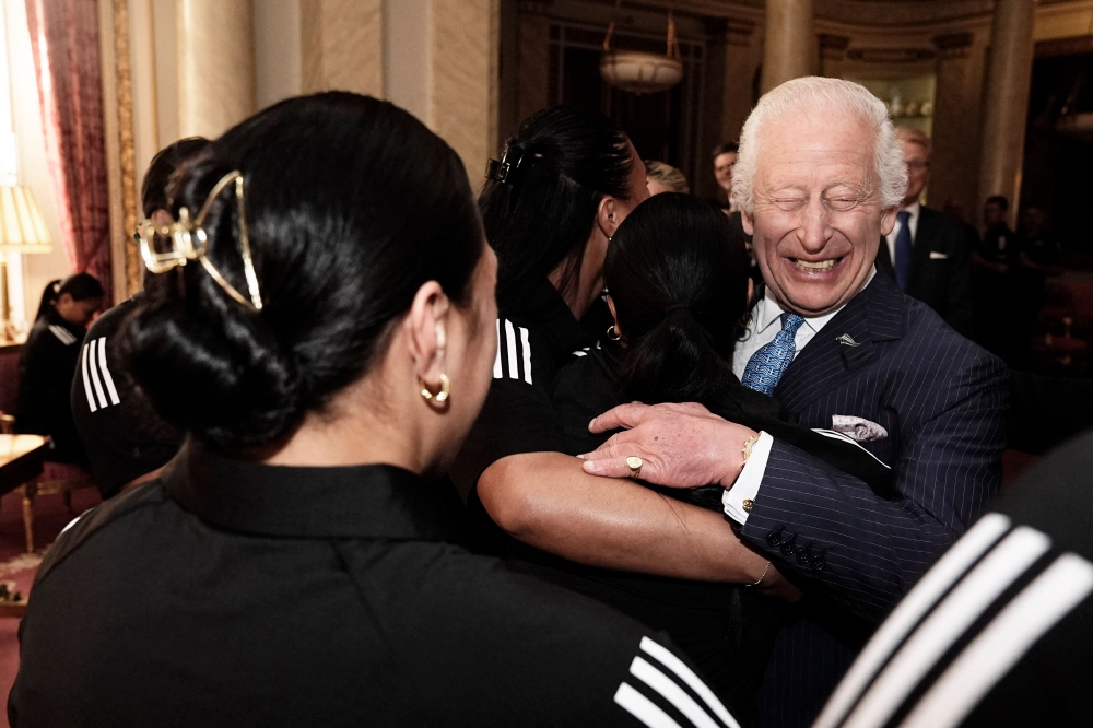 Britain's King Charles III reacts as he is hugged by members of New Zealand's Black Ferns rugby union team, at Buckingham Palace in central London on September 11, 2024. (Photo by Aaron Chown / POOL / AFP)