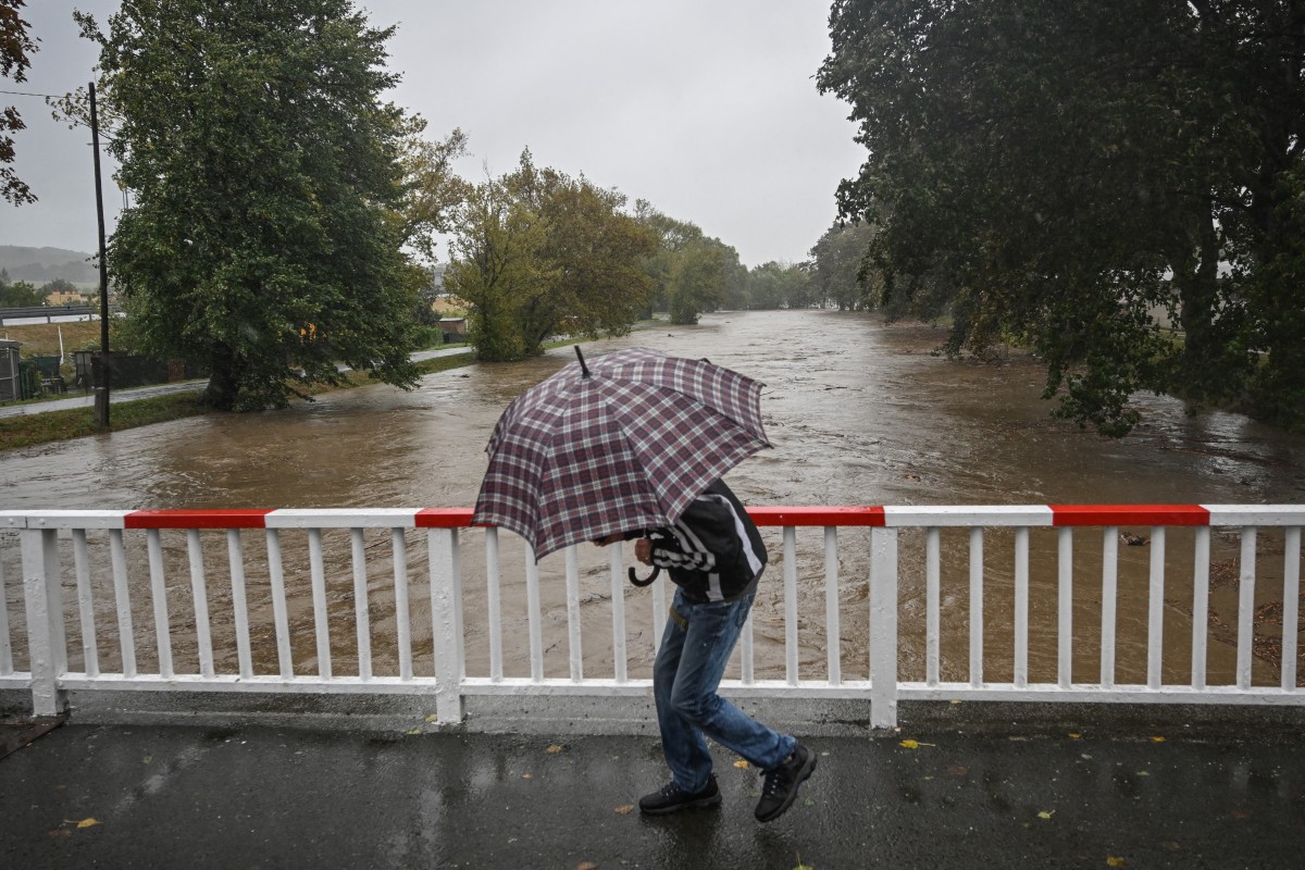 A man shelters from the rain under an umbrella as he runs over the bridge on September 14, 2024 in Krnov city as Central Europe faces heavy rainfall expected to cause floods. Photo by Michal Cizek / AFP.