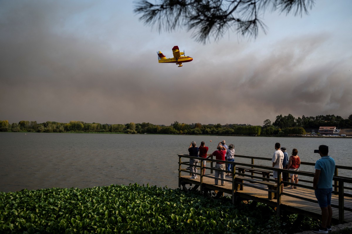 People watch a Spanish Canadair during a wildfire at Pateira de Fermentelos, Agueda in Aveiro on September 17, 2024. Photo by Patricia DE MELO MOREIRA / AFP.