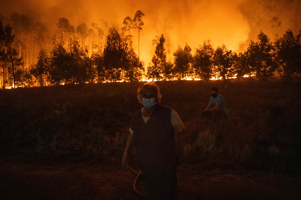 People stand watching the progression of a wildfire at Veiga village in Agueda, Aveiro on September 17, 2024. (Photo by Patricia De Melo Moreira / AFP)