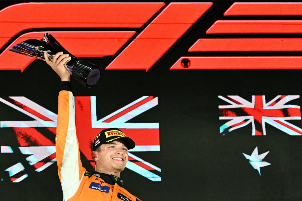 First placed McLaren's British driver Lando Norris celebrates on the podium after winning the Formula One Singapore Grand Prix night race at the Marina Bay Street Circuit in Singapore on September 22, 2024. (Photo by MOHD RASFAN / AFP)
 