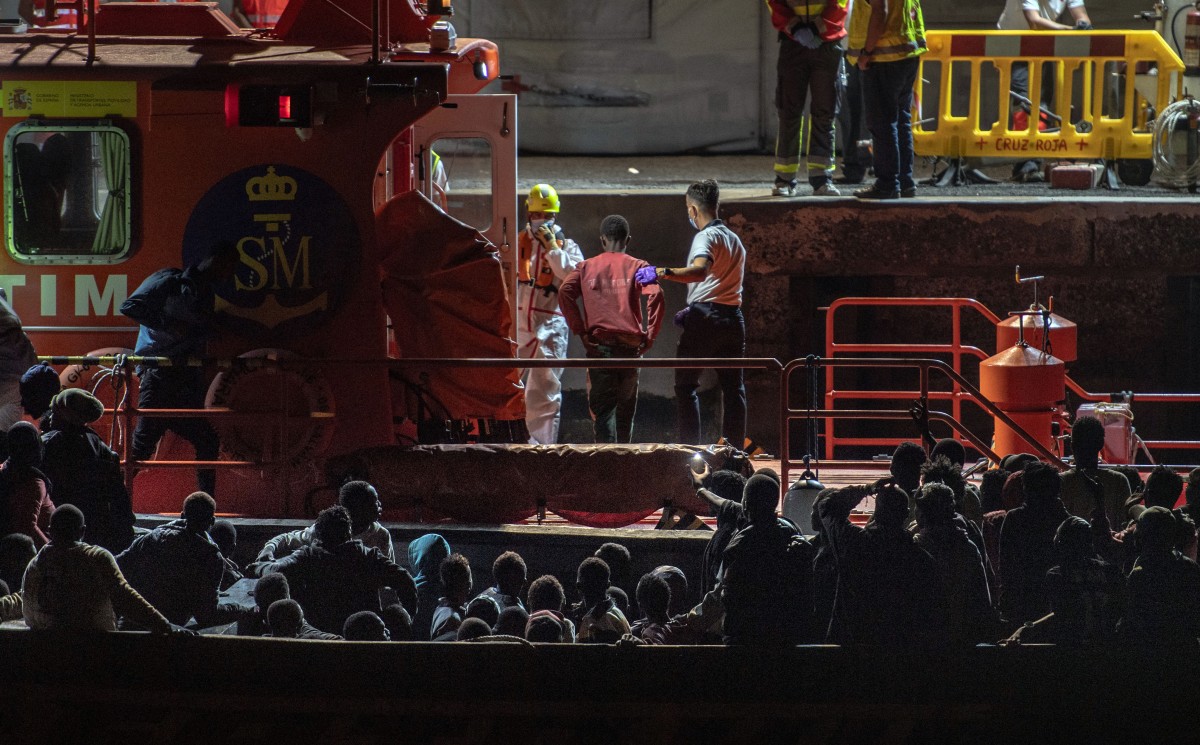 A captain of Spanish Salvamento Maritimo (Sea Search and Rescue agency) scorts one of the 17 minors (C) who arrived in a group of 133 migrants at La Restinga port, after being rescued by the Spanish Salvamento Maritimo Salvamar Adhara vessel off the coast of the Canary island of El Hierro, prior to being transferred to the San Andres Temporary Reception Center for Foreigners. (Photo by Antonio SEMPERE / AFP)
