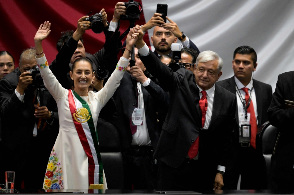 Mexico's new President Claudia Sheinbaum (left) and outgoing Mexican President Andres Manuel Lopez Obrador wave to the attendees during the inauguration ceremony at the Congress of the Union in Mexico City on October 1, 2024. (Photo by Alfredo Estrella/ AFP)