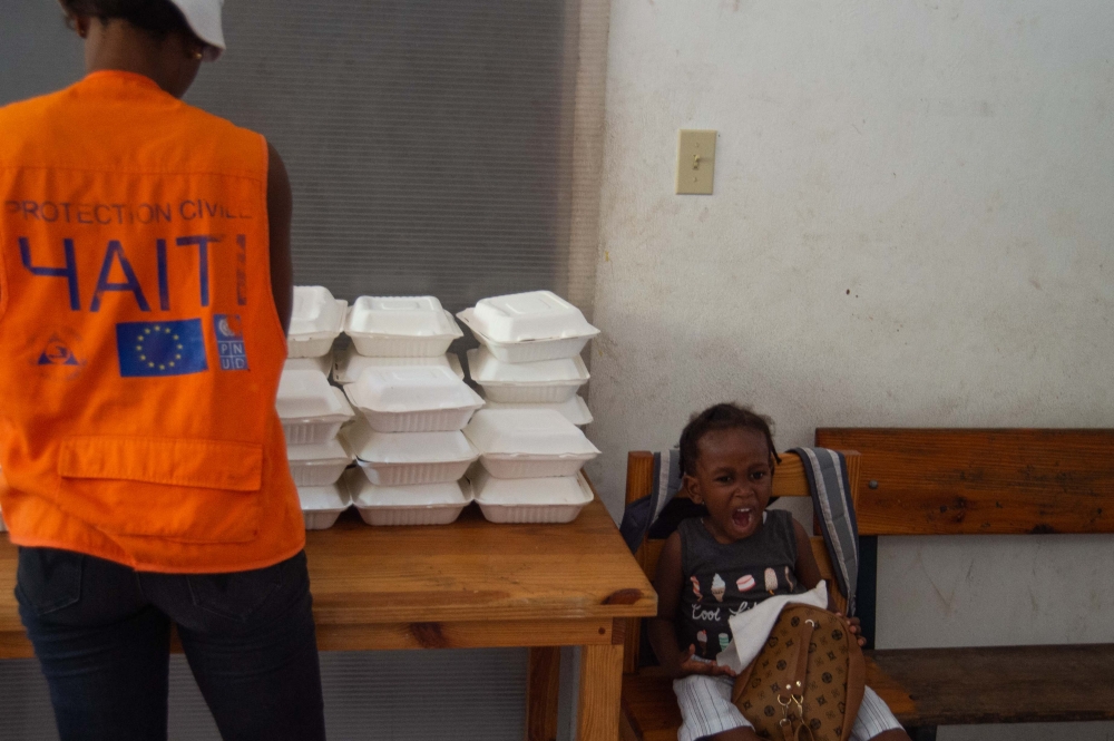 A child yawns while sitting next to food aid to be distributed in a displaced persons camp at the Lycée Marie Jeanne in Port-au-Prince on September 30, 2024. (Photo by Clarens Siffroy / AFP)
 