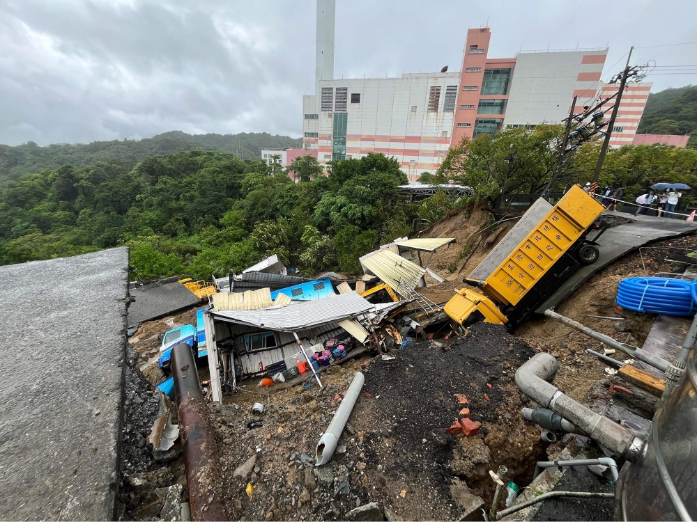 This handout photo taken and released on October 4, 2024 by Taiwanese city councillor Chen Yi shows public utility vehicles trapped in a landslide that was triggered by heavy rainfall after Typhoon Krathon swept across the island near Keelung City's Bureau of Environmental Protection. (Photo by Handout / Taiwanese city councillor Chen Yi / AFP)