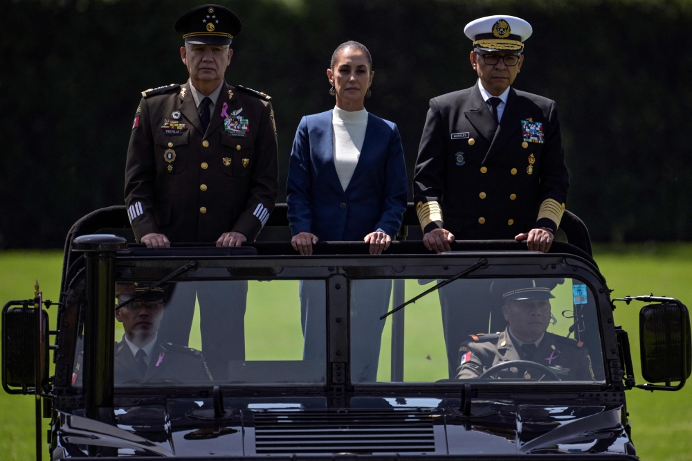 Mexico's President Claudia Sheinbaum (C), flanked by Defense Minister Ricardo Trevilla (L) and Secretary of the Navy Raymundo Pedro Morales (R), reviews troops during her inauguration ceremony as the new Supreme Commander of the Mexican Armed Forces at Campo Marte in Mexico City on October 3, 2024. (Photo by Yuri CORTEZ / AFP)
