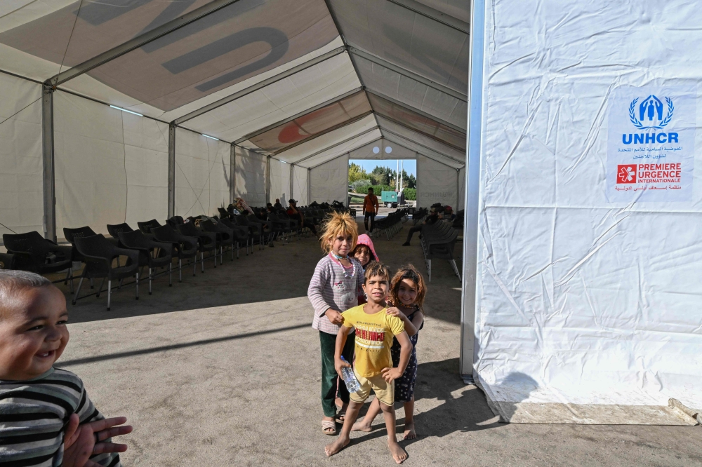 Children play around an emergency services tent set up at the Jdeidat Yabus border crossing in southwestern Syria as displaced people arrive from Lebanon on October 7, 2024. (Photo by LOUAI BESHARA / AFP)

