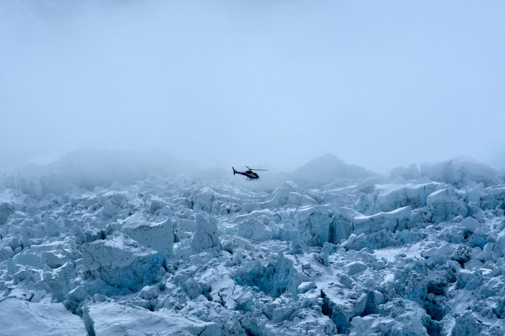 (Files) This photograph taken on May 2, 2021, shows a helicopter flying over the Khumbu glacier in the Mount Everest region. (Photo by Prakash Mathema / AFP) 