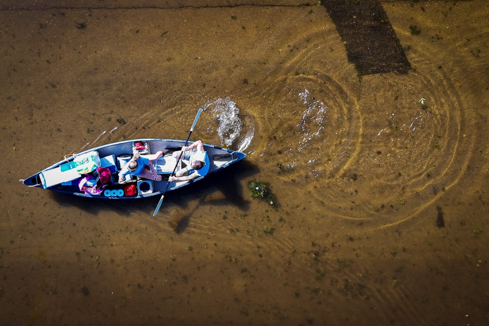 An aerial view shows people paddling through a flooded street in South Daytona, Florida, following the passage of Hurricane Milton on October 11, 2024. (Photo by Miguel J Rodriguez Carrillo / AFP)