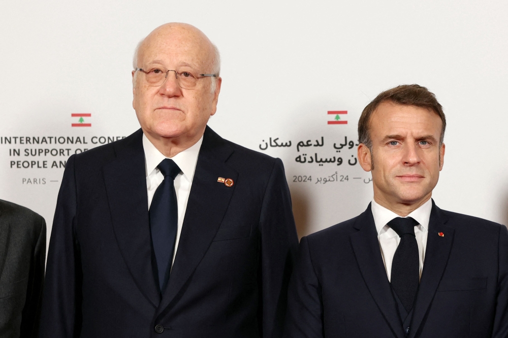Lebanon's Prime Minister Najib Mikati (L) and France's President Emmanuel Macron pose for a group photo during an international press conference in support of Lebanon, in Paris on October 24, 2024. (Photo by Alain Jocard / POOL / AFP)