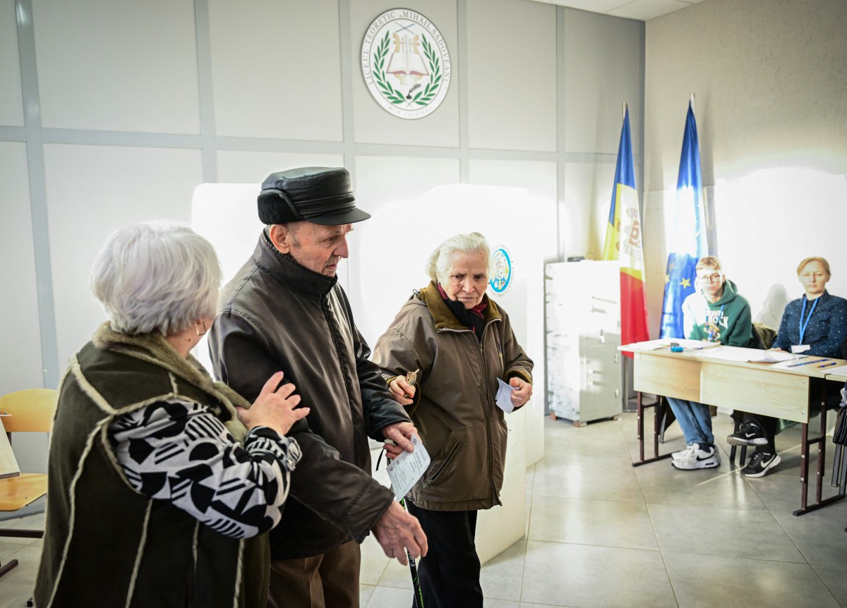 A Moldova's ederly man is helped as he walks to cast his vote for the presidential election at a polling station in Chisinau November 3, 2024. Photo by Daniel MIHAILESCU / AFP.
