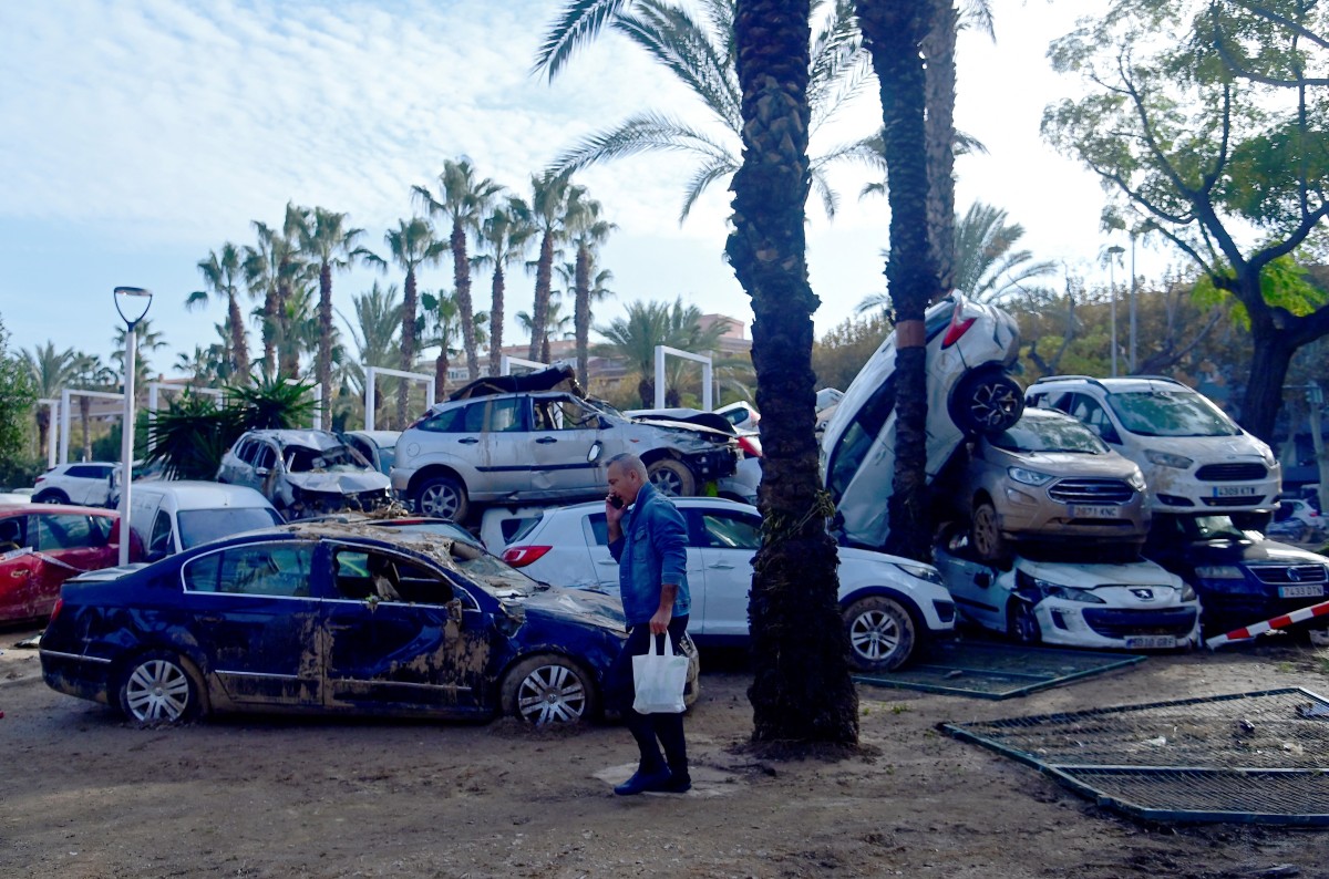 A man talks on the phone near car wreckages towed away following devastating flooding in Sedavi, south of Valencia, eastern Spain, on November 5, 2024. The death toll from Spain's worst floods in a generation has climbed to 217, according to rescuers. Photo by JOSE JORDAN / AFP.