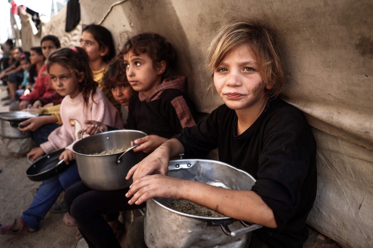 Palestinian children collect aid food at Bureij refugee camp in the central Gaza Strip, on November 6, 2024. (Photo by Eyad BABA / AFP)