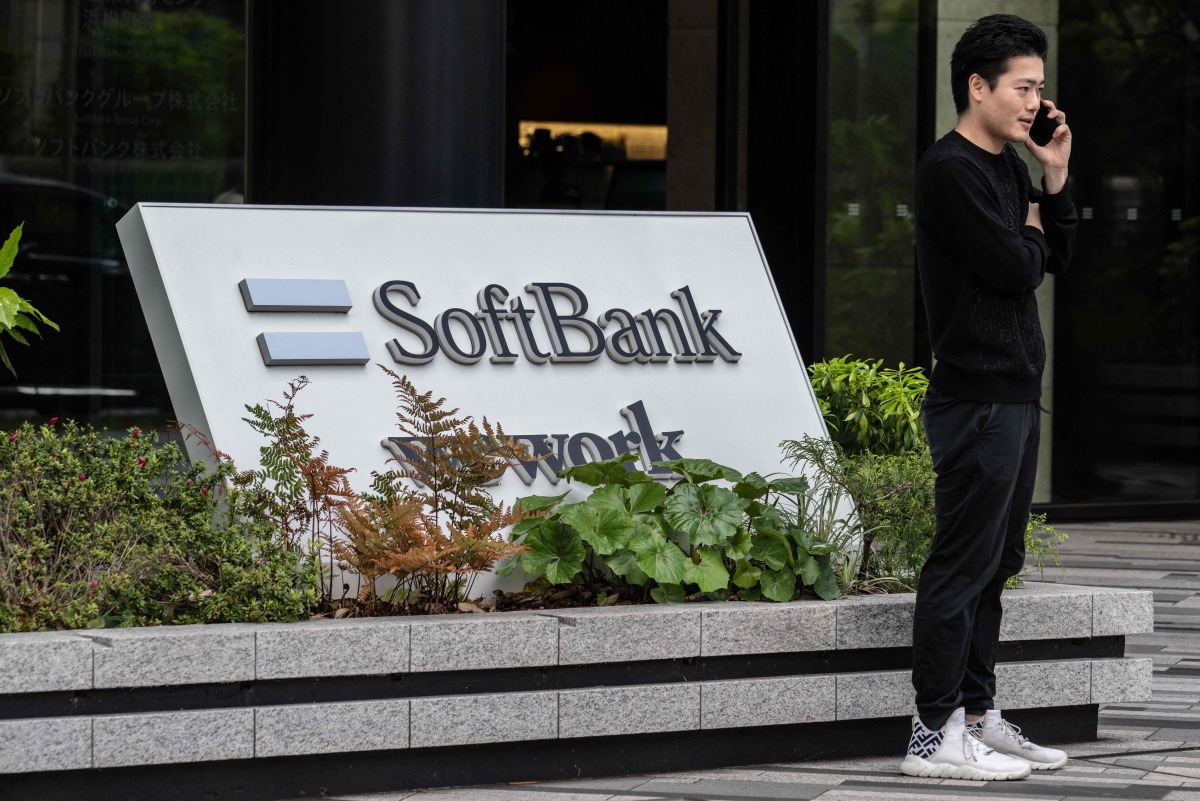 (FILES) This file photo taken on May 2, 2024 shows a man talking on his phone outside the headquarters for Japanese company SoftBank Group in Tokyo. (Photo by Yuichi YAMAZAKI / AFP)
