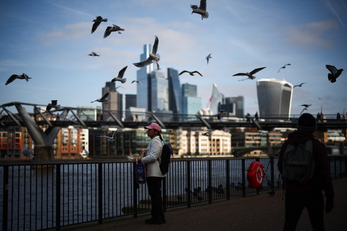File photo: Seagulls fly over people walking on the Southbank of the River Thames backdropped by the business and financial district in central London on November 15, 2024. Photo by HENRY NICHOLLS / AFP.
