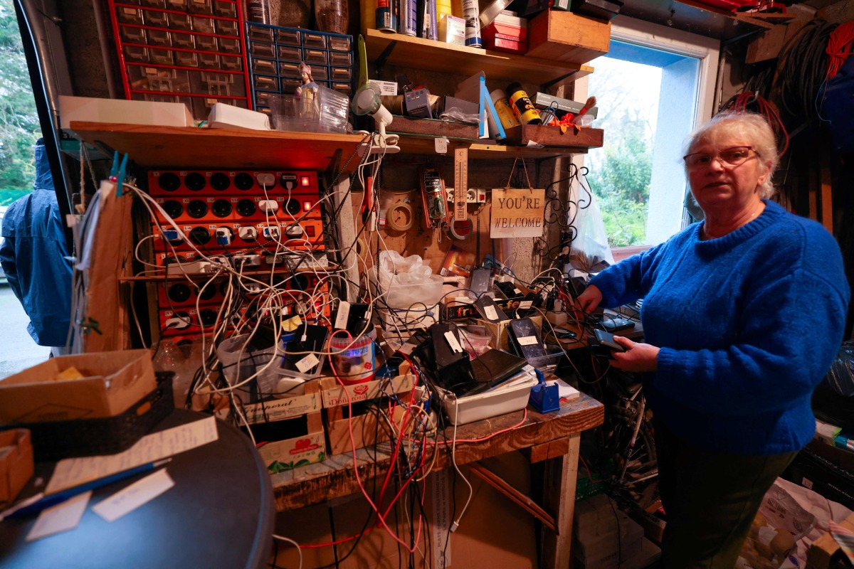 Brigitte Lips, nicknamed Mamie Charge, registers phones of migrants to be charged at her garage in Calais on November 26, 2024. (Photo by Denis Charlet / AFP)
