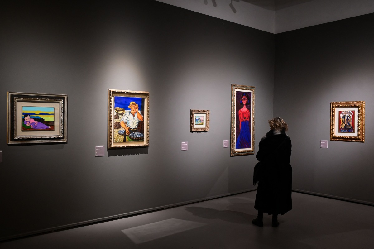 A woman looks at paintings during a press preview of the exhibition titled 