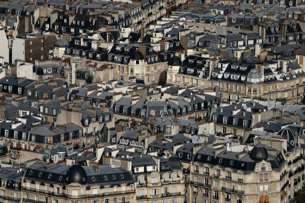 File: This photograph taken from the panoramic terrace of the Montparnasse tower, shows the zinc rooftops of Haussmannian buildings in Paris, on September 6, 2023. (Photo by Miguel Medina / AFP)