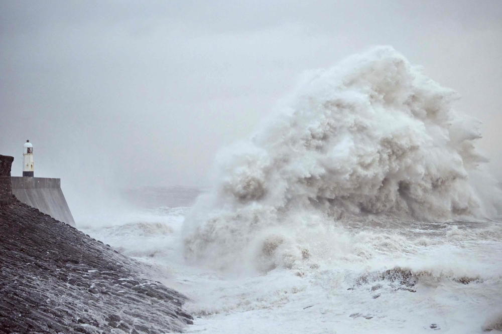 Waves crash against the sea wall and lighthouse at Porthcawl, south Wales, on December 7, 2024. (Photo by Ben Stansall / AFP)
 