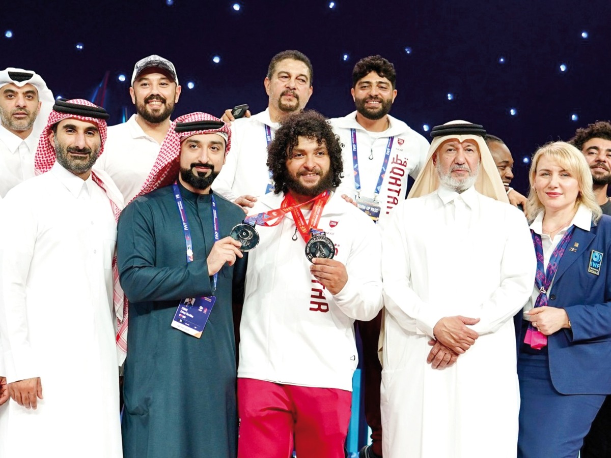 Fares Ibrahim celebrates with Qatar Olympic Committee's First Vice President and Vice President of the International Weightlifting Federation Mohamed bin Yousef Al Mana and Qatar Weightlifting Federation's Secretary General Jassim Ibrahim Al Mansouri. 