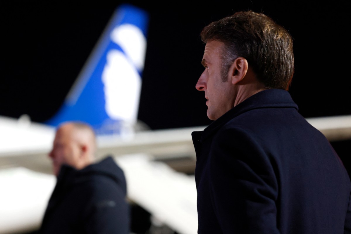 France's President Emmanuel Macron (R) looks on with the logo of Air Corsica on an aircraft in the background as he attends the Pope's departure ceremony at the Ajaccio airport, on the French island of Corsica, on December 15, 2024. (Photo by Ludovic MARIN / POOL / AFP)
