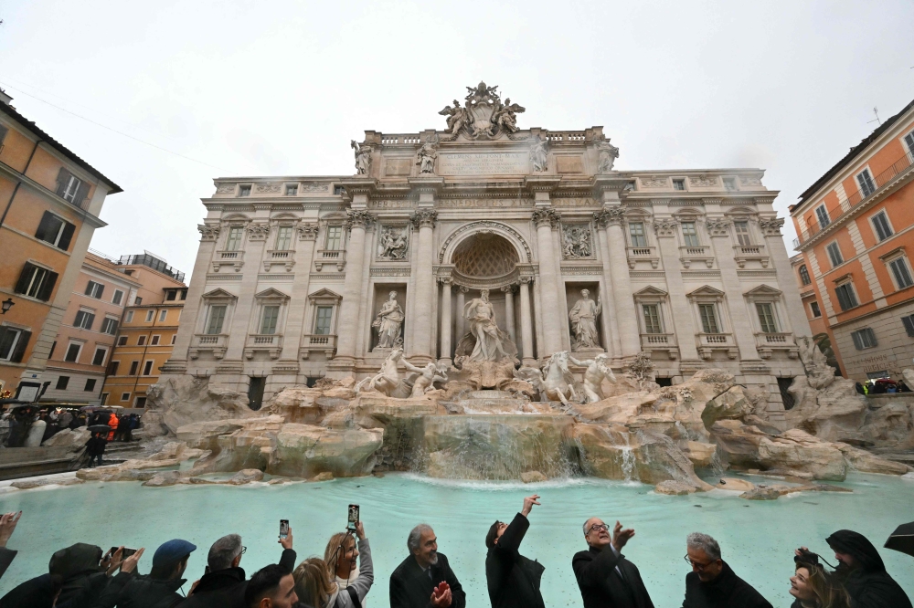 The mayor of Rome, Roberto Gualtieri (4th right) throws a coin in the Trevi fountain on the day of its reopening after renovation works in Rome, on December 22, 2024. (Photo by Alberto Pizzoli / AFP)