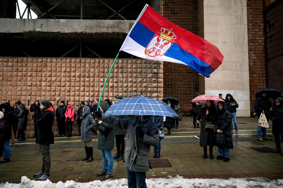 A Belgrade student waves a Serbian national flag as he blocks a major city intersection to silently honour the 15 victims of the tragedy at the Novi Sad railway station November 2024, in Belgrade, on December 25, 2024. (Photo by Andrej ISAKOVIC / AFP)

