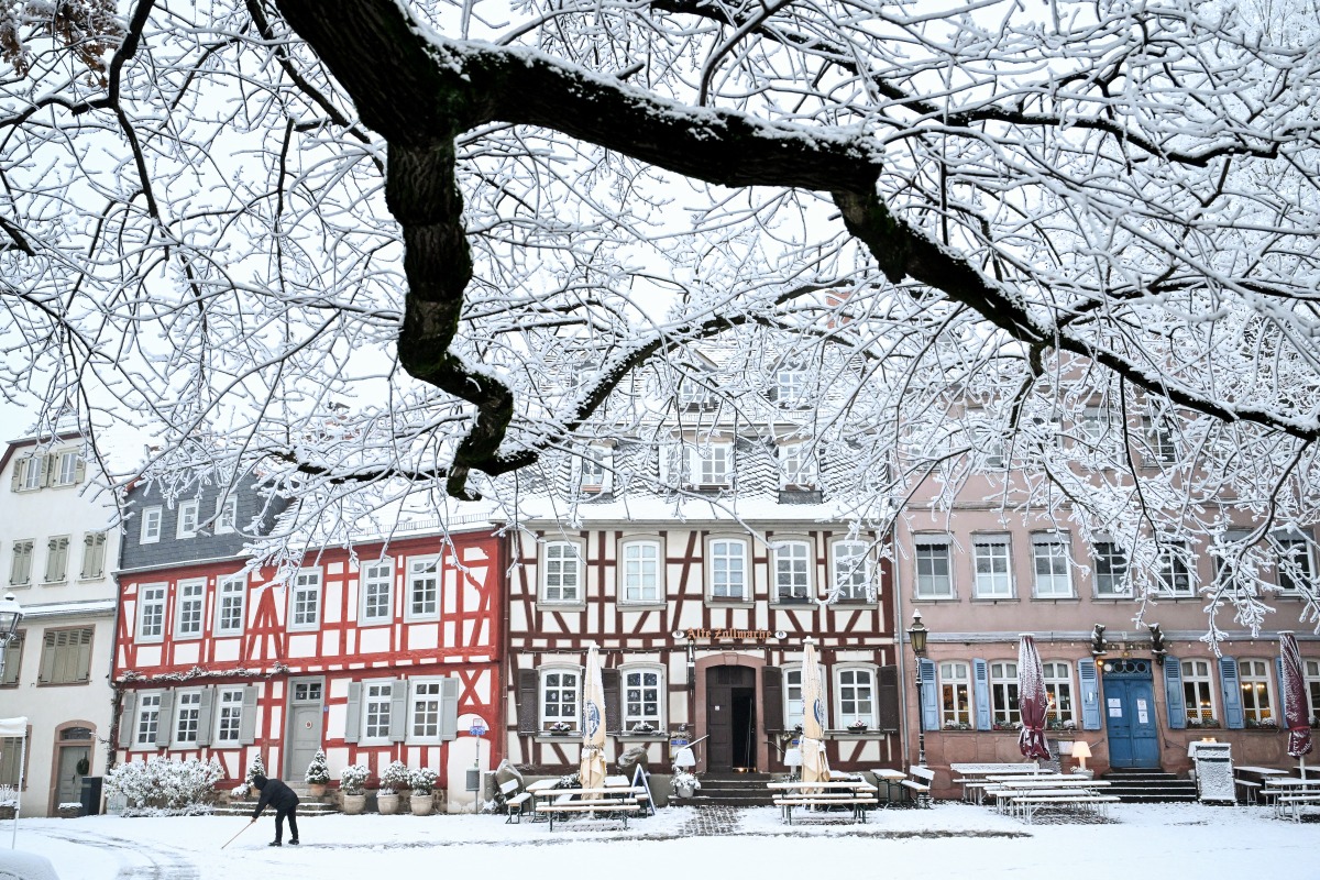 A person walks on a snow-covered street after snowfall in Frankfurt am Main, western Germany, on December 29, 2024. Photo by Kirill KUDRYAVTSEV / AFP.
