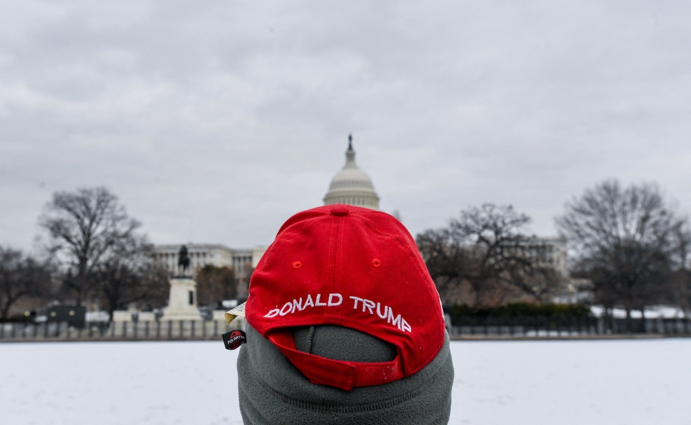 A man wearing a Trump hat looks at the US Capitol on January 17, 2025, in Washington, DC. (Photo by Matthew Hatcher / AFP)
 