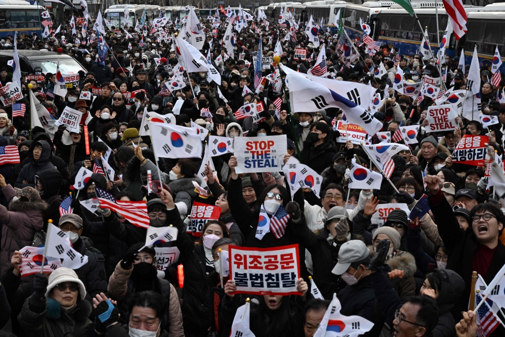 Pro-Yoon supporters wave flags as they gather on a road outside the Seoul Western District Court in Seoul on January 18, 2025. (Photo by Anthony Wallace / AFP)
 
